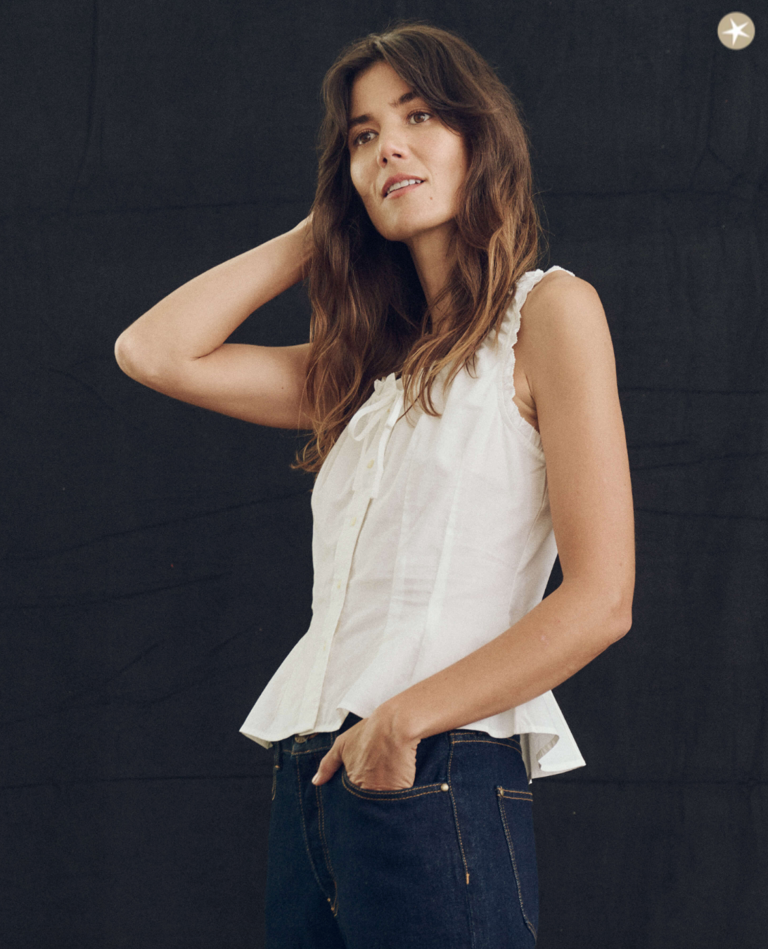 A woman in The Abbey Top from The Great Inc. poses against a black background, with her hand resting on his neck and a thoughtful expression, reminiscent of the relaxed lifestyle in Scottsdale, Arizona.