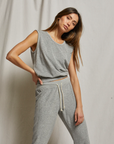 A woman poses against a light backdrop in Perfectwhitetee's ELLIE terry banded tank and matching gray sweatpants, featuring a scoop neckline and drawstring waist, looking at the camera with a relaxed expression.