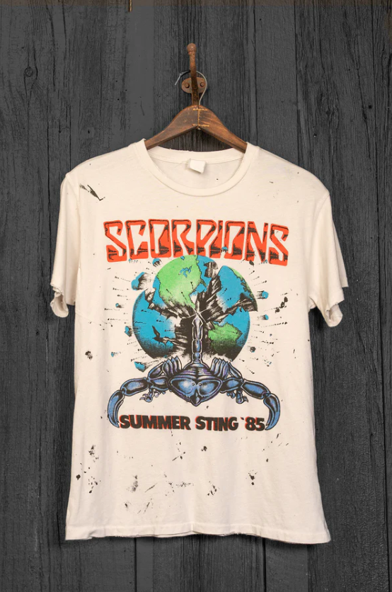 A vintage Made Worn Scorpions Summer Sting '85 band T-shirt, made in the USA, featuring an iconic design with the band's logo and graphics, hanging on a wooden hanger against a gray wooden background.