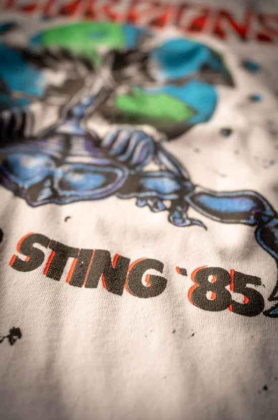 Close-up of a vintage Scorpions Summer Sting '85 tee by Made Worn, with the text "STING '85" in bold orange letters, featuring a graphic print of a scorpion in shades of blue and black.