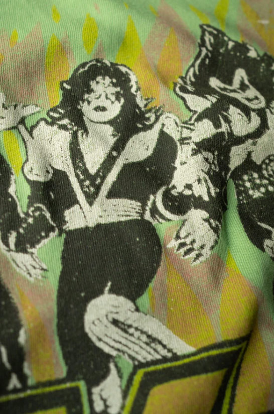 Close-up of a colorful fabric featuring a repeated black and white graphic print of a person in a dynamic pose, possibly singing, with a background of yellow and green flames in Made Worn style.