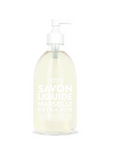 A 16.7oz clear glass pump bottle with a white pump dispenses pale yellow liquid soap labeled "Savon Liquide Marseille Extra Pur Fleur de Coton" in white text. Infused with gentle vegetable oils, created by Cie Luxe Brands, it sits against a plain white background.