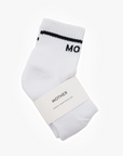 A pair of classic white Baby Steps Ankle socks with black stripes near the top, partially displaying the word "Mother". The socks are neatly folded and secured with a white label that reads "Mother" and "Knock Your Socks Off". They are displayed against a plain white background.