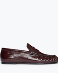 The Freda Salvador Sydney Crinkle Loafer is a dark brown Italian leather slip-on with a low heel, penny strap, and visible stitching. Shown from the side on a white background, it's perfect for effortless sophistication.