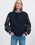 Rag & Bone Scarlet Varsity jacket with faux leather sleeves styled with blue jeans, hands in pockets.
