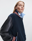 Scarlet Rag & Bone varsity jacket with faux leather sleeves styled over a blue shirt, worn with confidence.