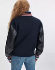 Scarlet varsity jacket with faux leather sleeves by Rag & Bone, shown from the back with blue jeans.