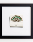 A framed acrylic artwork depicts an ornate matchbook cover with the text "The Inn on The Green" written in green and brown lettering, surrounded by decorative flourishes. The matchbook is centered on a white background and encased in a simple Match South Art Square Blk Frame.