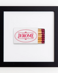 Framed matchbook with "Hotel Jerome Aspen" printed in red text on a white background. The matches, which have burgundy tips and are neatly arranged, are displayed in an elegant black frame. This **Art Square Blk Frame** by **Match South**, akin to fine prints, is mounted on a crisp white backdrop for a sleek finish.