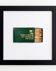 A framed Art Square Blk Frame with a green cover that reads "The Lodge at Pebble Beach" in gold lettering, accompanied by a logo above the text. The matchbook is partially open, revealing several wooden matches inside, some of which appear used. This unique piece could complement a collection of vintage prints or acrylic displays.