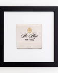 A framed matchbook from The Plaza Hotel in New York. The matchbook is centered in the white background of the black square frame, with "The Plaza" logo and "NEW YORK" text visible. This elegant piece provides a nostalgic charm similar to vintage prints preserved under acrylic, presenting itself as the Art Square Blk Frame by Match South.