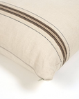 The Vourkari Pillow by Libeco Home is beige with brown and black stripe accents, featuring a visible zipper closure along one edge, shown on a white surface.