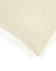 Close-up of the corner of the Gus Pillow by Libeco Home in beige fabric against a white background, showcasing its textured surface and stitched seam.