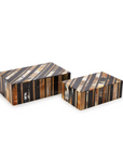 The Horn Covered Box set by Two's Company includes two handcrafted boxes with lids, featuring diagonal stripes in brown, black, white, and tan. One box is larger than the other, making them perfect as decorative storage accents.