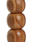 The Pillar Candleholder by Two's Company features five stacked, rounded acacia wood segments with a smooth finish, forming a modern geometric design inspired by mid-century modern style.