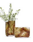 Two Swirl Blown Glass Vases by Two's Company, one tall holding white flowers and one short and empty, both with brown marbled designs, are displayed on a white background—artful home decor accents.