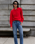 A woman in a Sold Out NYC Cashmere Polo and jeans.