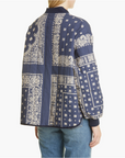A person shown from the back wears The Quilted Bomber by The Great Inc.—a blue pure cotton jacket with white paisley and geometric bandana print—paired with blue jeans.