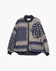 The Great Inc. Quilted Bomber is a navy blue pure cotton jacket with cream patchwork bandana print, paisley and geometric details, black ribbed collar, cuffs and hem, and a front zipper closure.