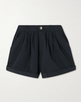 The Paige Short by DOEN is a pair of dark navy blue tailored shorts featuring a button and zip closure, front pleats, side pockets, and rolled-up cuffs, shown against a plain light background.
