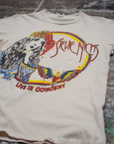 The Made Worn Stevie Nicks Tee is a cream vintage unisex 90s-fit shirt featuring a graphic of a woman, colorful designs, and "Stevie Nicks" and "Live in Concert" text on the front, shown on a paint-splattered surface.