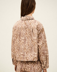 A person with long brown hair, seen from behind, wears the BA&SH Jacket Tullia—a light pink and brown paisley-patterned 100% cotton set—styled against a plain background.