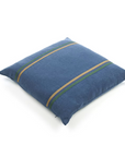 The Max Pillow by Libeco Home is a square blue 25x25 floor cushion featuring two parallel yellow and green diagonal stripes, shown on a white background. Pillow insert included.