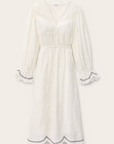 The BA&SH Dress Prisco is a long-sleeved, white dress with an elasticated waist, V-neck, button-down front, scalloped edges on cuffs and hem, subtle embroidery, and lace trim for an elegant touch.