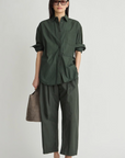 Oversized button down shirt by Apiece Apart styled with wide pants and gray bag in a casual, modern setting.