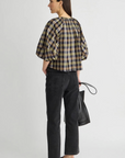 Apiece Apart Nele Lantern Sleeve Top in white, styled with black jeans and flats, model facing away.