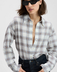 The Everything Shirt by Sold Out NYC, white and half unbuttoned, styled with dark high-waisted jeans and sunglasses.