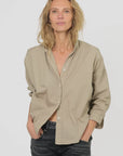Monday12 Zoe Shirt in Army Beige styled with black jeans, worn by a woman with wavy blonde hair against a light background.