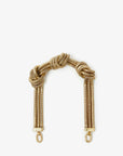 The Clare Vivier Shortie Strap S24 is a gold-toned coiled metal handbag strap with central knotted accents and brass spring links for easy attachment, shown against a white background.