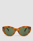 The Sophia Sunglasses by Clare Vivier feature large, round green-tinted lenses and brown tortoiseshell frames made from bio-based material with full UVA/UVB protection, shown on a plain white background.
