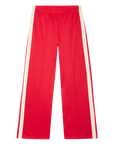 The Great Inc. The Wide Leg Track Pant in red features wide legs, white side stripes, and an elasticated waistband. Shown laid flat on a white background.