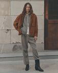 Fleece Sport Sweatpant by The Great Inc. in a relaxed setting, styled with a brown jacket by a stone wall and door.