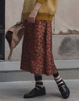 The Great Inc. yellow Canary Skirt styled with sweater and loafers, casual modern look, paper produce bag in hand.