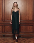 The Legacy Dress by The Great Inc. styled with white socks, brown loafers, and warm wood paneling in a cozy setting.