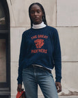 The Great Inc. Fleece Rookie Growling Panther sweatshirt styled casually with jeans by a stone wall.