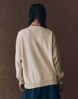 A woman wears The Great Inc. Stable Pullover, an oversized crew sweater with a playful horse-head intarsia design.
