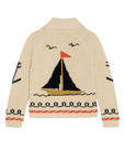 The Great Inc. Sailboat Lodge Cardigan in a beige cotton blend features a large hand-embroidered sailboat with black and yellow sails, an orange flag, bird motifs, and black and orange decorative waves on the hem and sleeves.