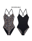Two views of The Reversible Lace Up by The Great Inc.: one side features a leopard print, the other is solid black with leopard trim. Made from recycled materials for a flattering fit. "REVERSIBLE" appears above the swimsuits.