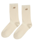 Cream trouser socks with brown TG monogram near the top, by The Great Inc., classic finishing touch for any outfit.