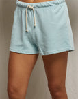In a neutral backdrop, someone wears Perfectwhitetee's Layla Terry Short—mid-thigh light blue lounge shorts with a drawstring, crafted from soft French terry cotton for a relaxed, stylish look.