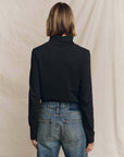 The Great Inc. turtleneck sweater in black, styled with blue jeans, back view in a casual setting.