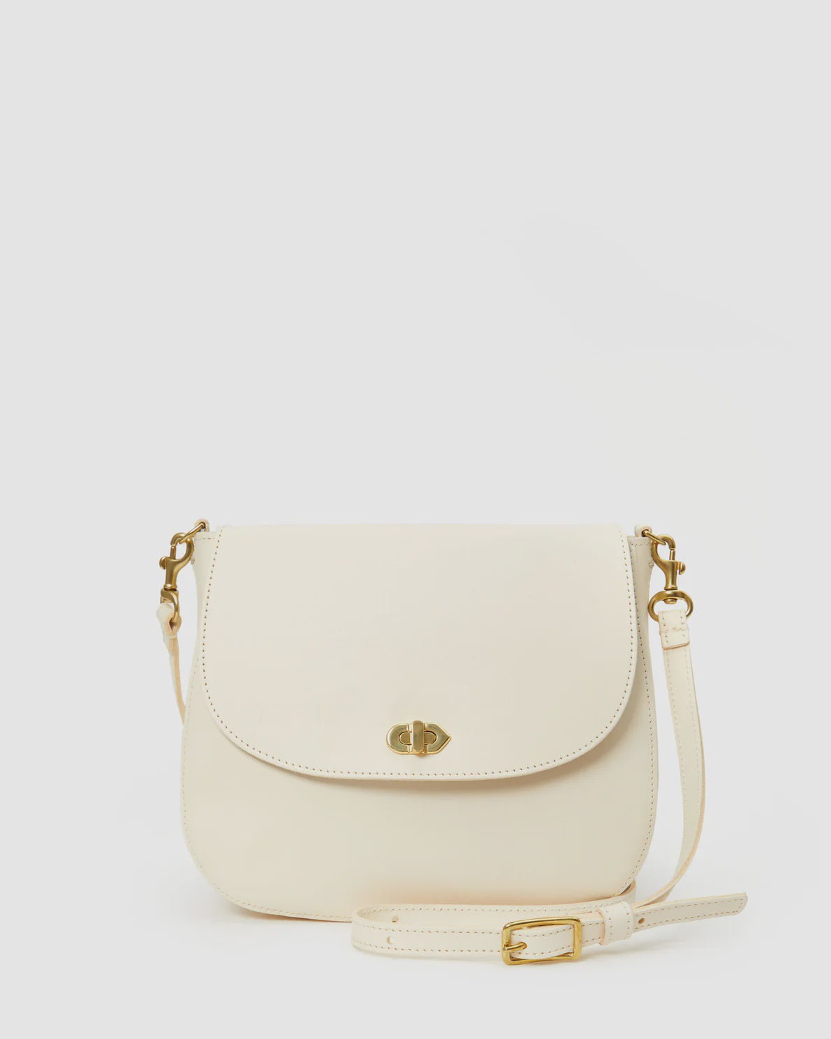 A Turnlock Louis Cream crossbody purse by Clare Vivier with a flap closure and a gold clasp, displayed against a solid white background. The purse has an adjustable strap with a buckle and includes a convenient back pocket.