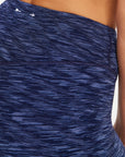 Close-up of a person wearing The Upside MYSTERE REVERSIBLE 25IN PANT—high-waisted, moisture-wicking blue patterned leggings with visible seams and a small white logo by the waistband.