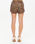 A person is standing with their back to the camera, wearing The Upside PANTHERA BILLIE RUN SHORT and white sneakers, set against a plain white background.