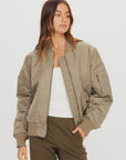 The Upside TRIBUTE BOMBER JACKET in recycled nylon, styled with a white tank and olive pants on a neutral backdrop.