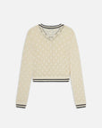 The Rookie Cardi by FRAME is a cream-colored lightweight knit with a delicate lacy pattern, V-neckline, and black trim on the collar, cuffs, and hem—offering timeless style.